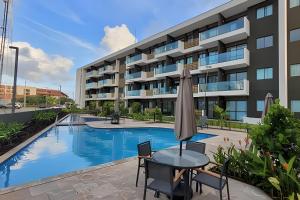 ein Apartmenthaus mit einem Pool und einem Tisch mit einem Sonnenschirm in der Unterkunft Mana Beach-Muro Alto in Porto De Galinhas