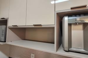 eine Küche mit weißen Schränken und einer Mikrowelle in der Unterkunft Mana Beach-Muro Alto in Porto De Galinhas