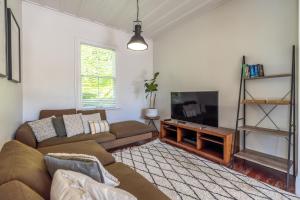 a living room with a couch and a flat screen tv at Nikau Grove - Onetangi Holiday Home in Onetangi