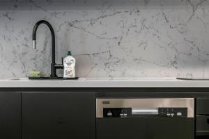 キャンベラにあるLuxury 1-Bedroom Apartment in Allara St Canberraの食器洗い機の隣に洗剤のボトル1本付きのキッチンシンク +28枚の写真