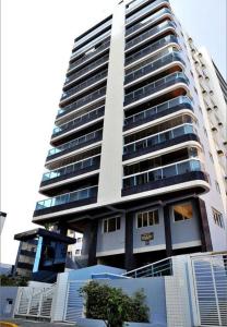 a tall white building with a lot of windows at Apto Pé na Areia com Vista Mar, Churrasqueira e Espaço para 8 Pessoas in Praia Grande