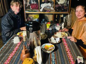 two men sitting at a table with a meal at Salkantay Glamp in Colcapampa +49 photos