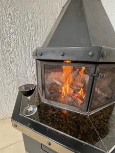 a glass of wine next to a wood stove at Residencial Encantos Linha Bonita - Vista que acalma, ambiente que encanta! in Gramado