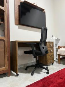 a black chair sitting at a desk with a flat screen tv at Sossego e Boa Vista in Ilhabela