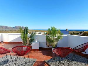 a patio with chairs and palm trees on a roof at Cala Grande suites 3 hab, vistas al mar y terraza in El Cabo de Gata
