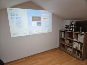 a large screen hanging on a wall in a room at One House, a comforting place For someone going through a major turning point in Wabu