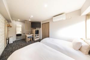 a hotel room with two beds and a desk at Hotel Cerezo in Tokyo