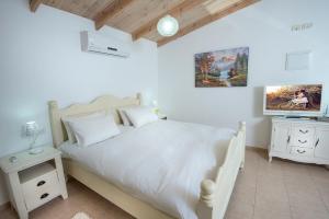 a bedroom with a white bed and a tv at Song of Galilee in Elifelet +106 photos