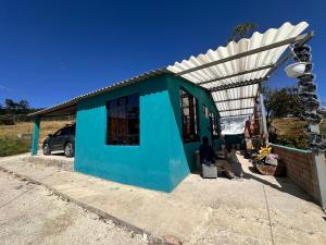 Ein blaues Gebäude mit einem Mann, der draußen sitzt. in der Unterkunft El Refugio de Paipa Lugar de Descanso y Tranquilidad in Paipa