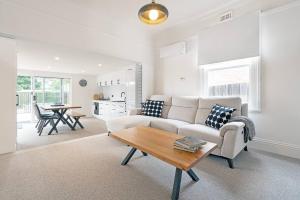 una sala de estar con un sofá y una mesa en Wilson Cottage - Historic Charm meets Modern Comfort, en Sandy Bay