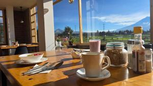 a wooden table with cups and utensils on it at Cuscungo Cotopaxi Hostel & Lodge in Chasqui