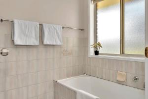 a white bathroom with a tub and a window at Vinea Vista - Hillside Homestead amid Rural Beauty in Lenswood +22 photos