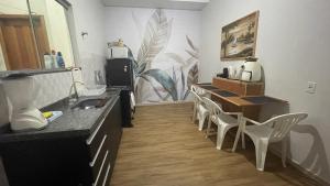 a kitchen with a sink and a counter with chairs at Flat hotel Victoram in Rio Branco