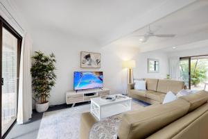 a living room with a couch and a tv at 4 Kurrambah at Noosa Sound in Noosaville