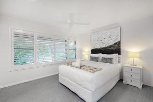 a white bedroom with a large white bed and a window at 4 Kurrambah at Noosa Sound in Noosaville +8 photos
