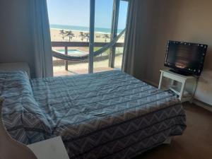 a bedroom with a bed and a television and a balcony at Chacras del Mar 4x4 in Mar Azul +43 photos
