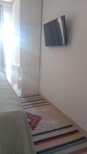 a room with a bed and a television on a wall at Apartamento Solar das Artes in Morro de São Paulo