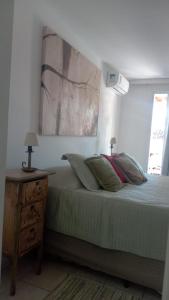 a bedroom with a bed with a nightstand and a painting at Apartamento Solar das Artes in Morro de São Paulo +5 photos