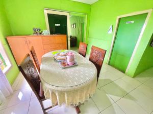 a dining room with a table and chairs with a plate of food at Villa DiDu, Puncak 2 in Cikuray