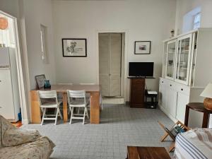 a living room with a table and chairs and a television at Arcachon: Charmante Maison T3 Proche Plage et Commerces, 2 Chambres, Wi-Fi, Idéale Familles - FR-1-319-35 in Arcachon