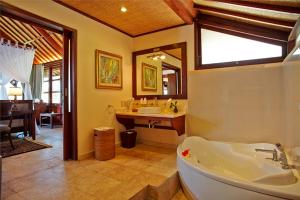 a bathroom with a tub and a sink and a mirror at Bagus Jati Health & Wellbeing Retreat in Tegalalang