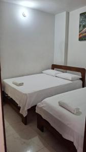 two beds in a room with white walls at Apartamento Manjarrez 4 Compartido in Mompos