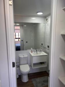 a bathroom with a toilet and a sink and a mirror at Depto equipado - WiFi rápido - 1 min de UCM - piscina rooftop in Talca