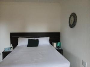 a bedroom with a bed with a clock on the wall at Mama Olly & Sons Guest House in Vosburg
