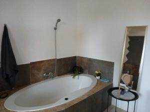 a large bath tub in a bathroom with two stools at Mama Olly & Sons Guest House in Vosburg