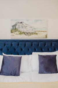 a bed with a blue headboard and two pictures on the wall at Gatekeepers Cottage - Idyllic 4 Bed Rural Escape! in Cropthorne