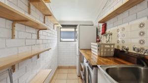 Una pequeña cocina con fregadero y refrigerador. en Barefoot On First - Pool, Beach, Family - Friendly, en Sawtell 12 fotos más