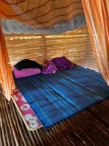 a small bed in a tent with a blanket at Mondulkiri tour and family homestay in Krong Saen Monourom