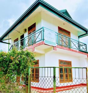 a white building with a balcony and a fence at Ceyonra Evermist Residence in Nuwara Eliya
