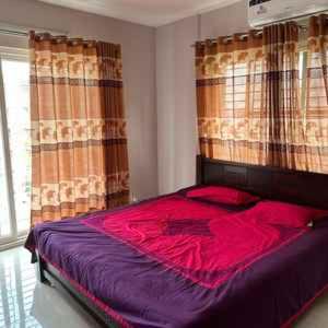una camera da letto con un grande letto con lenzuola rosse di Simply Apartement Rent a Dhaka