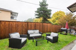 a backyard with chairs and a table and a grill at Beautiful Vancouver Cedar Cottage House in Vancouver