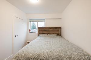 a bedroom with a bed in a white room at Beautiful Vancouver Cedar Cottage House in Vancouver