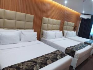 two beds in a hotel room with white sheets at Perc Hotel in Pinamungahan