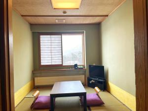 a room with a table and chairs and a window at Pension Puutaro in Zaō Onsen