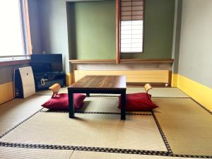 a room with a wooden table and two red cushions at Pension Puutaro in Zaō Onsen