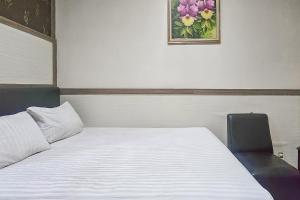 ein Schlafzimmer mit einem Bett, einem Stuhl und einem Bild in der Unterkunft Wisma Brata Mitra RedDoorz in Sukabumi