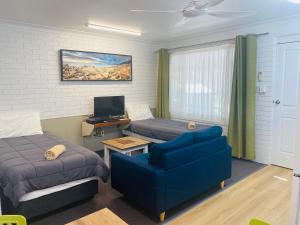 a hotel room with two beds and a blue chair at Iluka Motel in Iluka