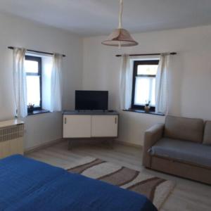 a bedroom with a bed and a couch and windows at Szira Porta in Hollókő