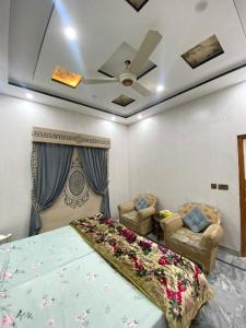 a bedroom with a bed and two chairs at Gulistan Inn in Faisalabad