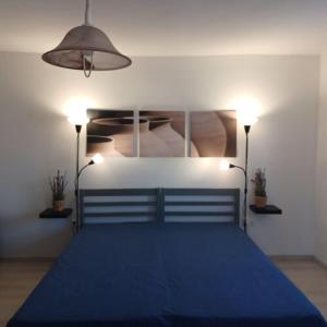 a bedroom with a blue bed with two lights at Szira Porta in Hollókő