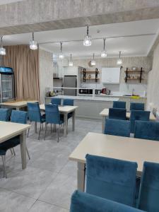 a cafeteria with blue chairs and tables and a kitchen at HOTEL MERCURI-MERIDIAN in Bukhara