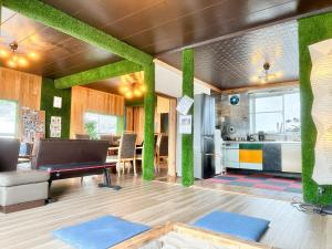 a living room with green walls and a kitchen at ゲストハウスみどり in Iiyama