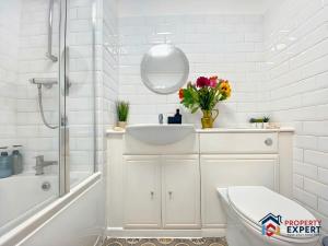 een witte badkamer met een wastafel en een spiegel bij BridgeView Central Cambridge with Parking Off Site F6 in Cambridge