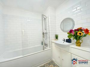 een badkamer met een bad, een wastafel en een spiegel bij BridgeView Central Cambridge with Parking Off Site F6 in Cambridge +13 foto's