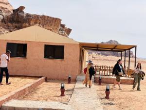 a group of people standing outside a building in the desert at Wadi Rum Salman camp in Wadi Rum