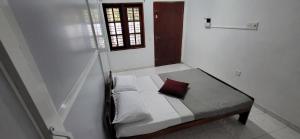 a small white bed with a red pillow on it at Villa De Wick's in Kimbulapitiya
